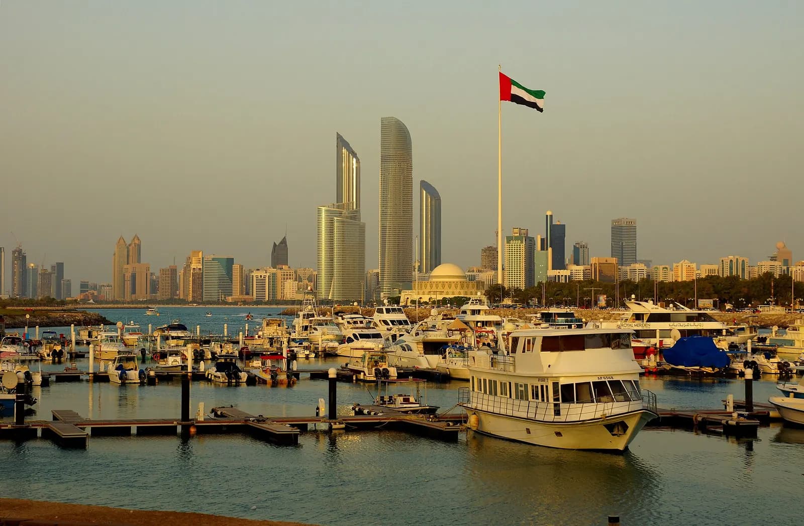Abu Dhabi towers and a marina seen from the breakwater at sunset