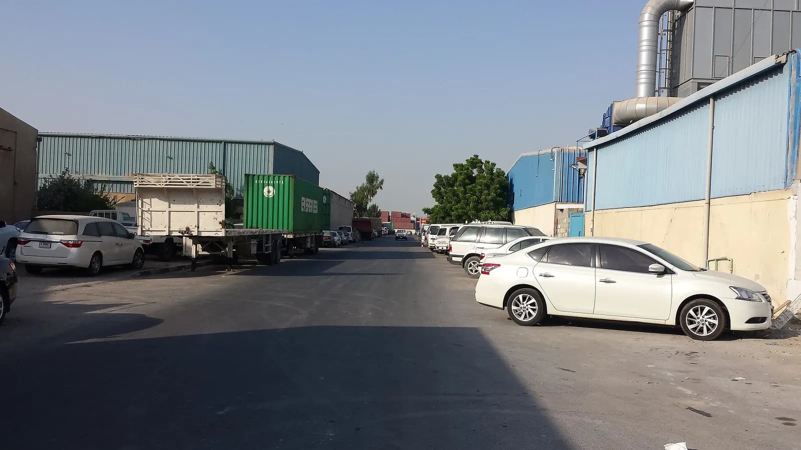 Street of small factory and warehouse units in Ras Al Khor Industrial Area, Dubai, with parked cars and a container truck