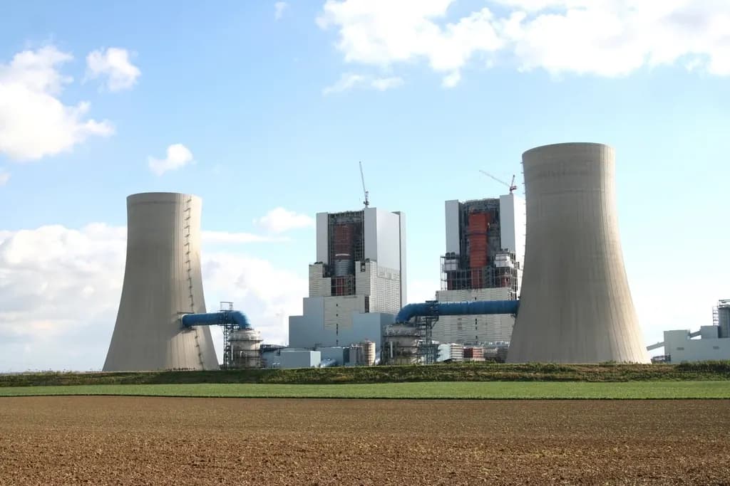 Power station with two large cooling towers and boiler houses under a blue sky