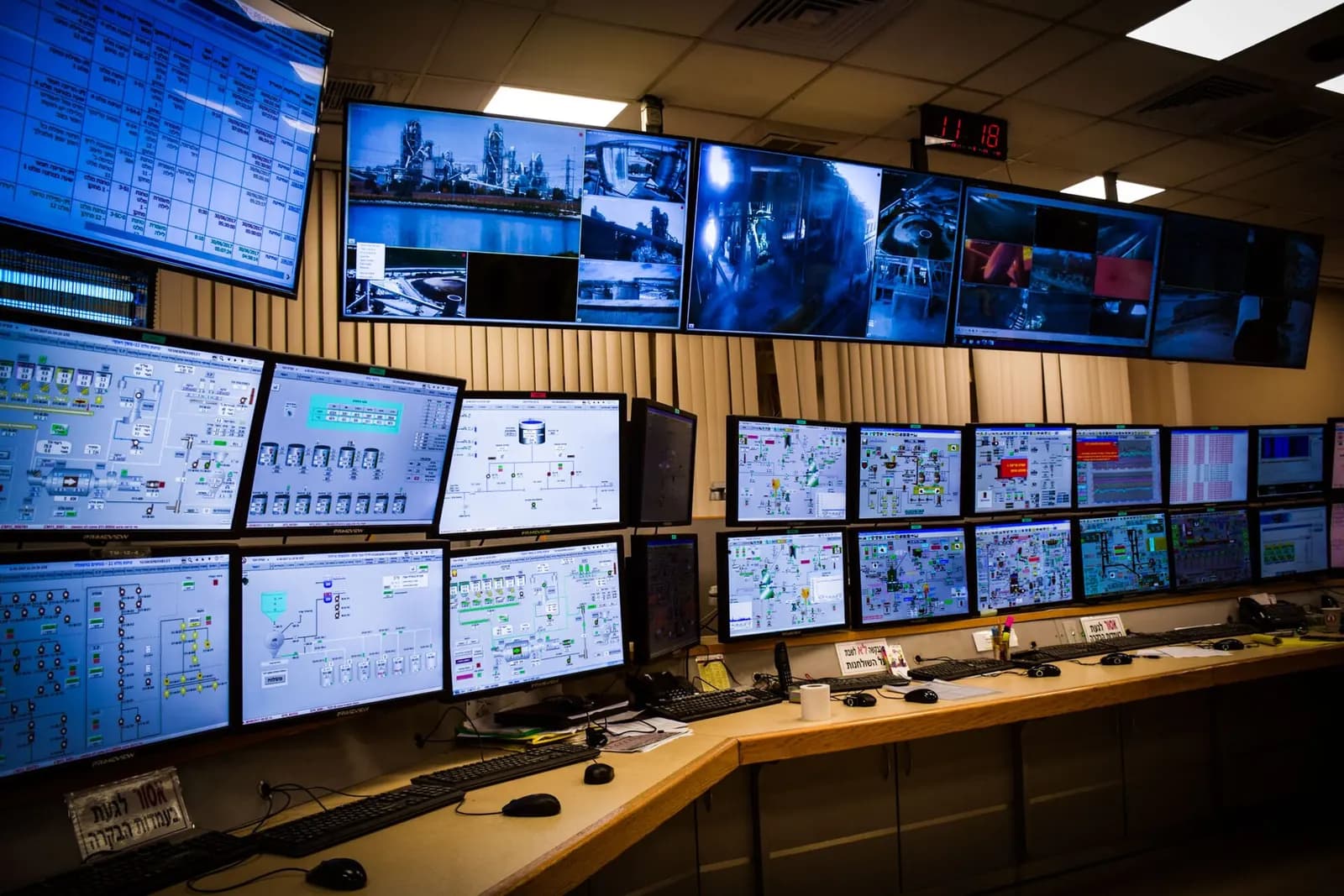 Process control room with rows of monitors showing plant graphics and trends above an operator desk