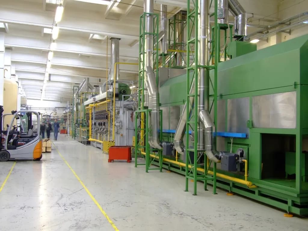 Clean factory hall with green process equipment, yellow gas lines and a forklift