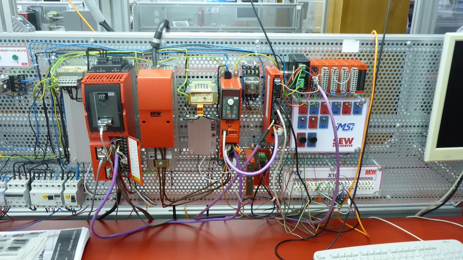 Electric drives training bench in a university lab, with frequency inverters, I/O modules and patch wiring on a perforated panel