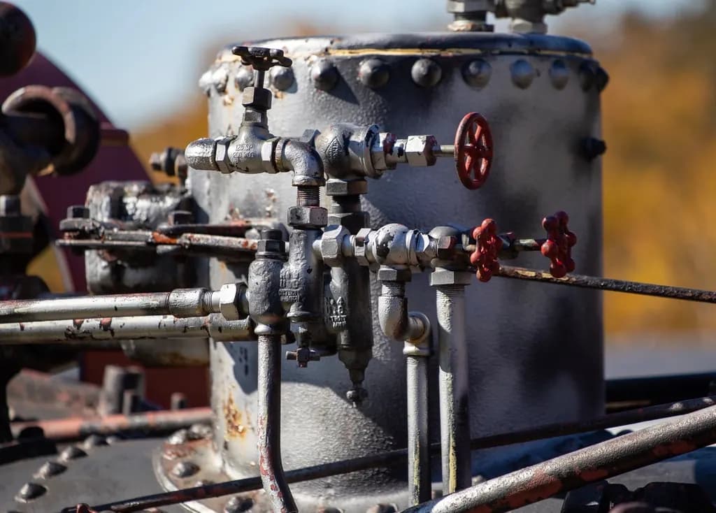 Weathered industrial pipework with small valves and a pressure vessel