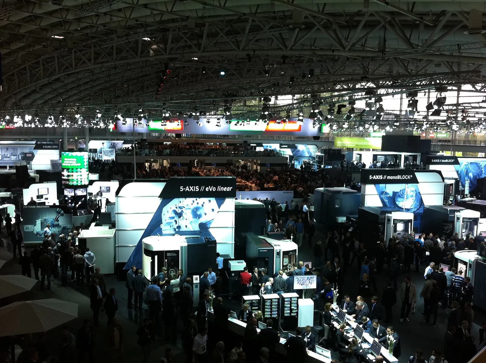 Busy exhibition hall at the EMO machine tool fair in Hannover with machine stands under a high roof