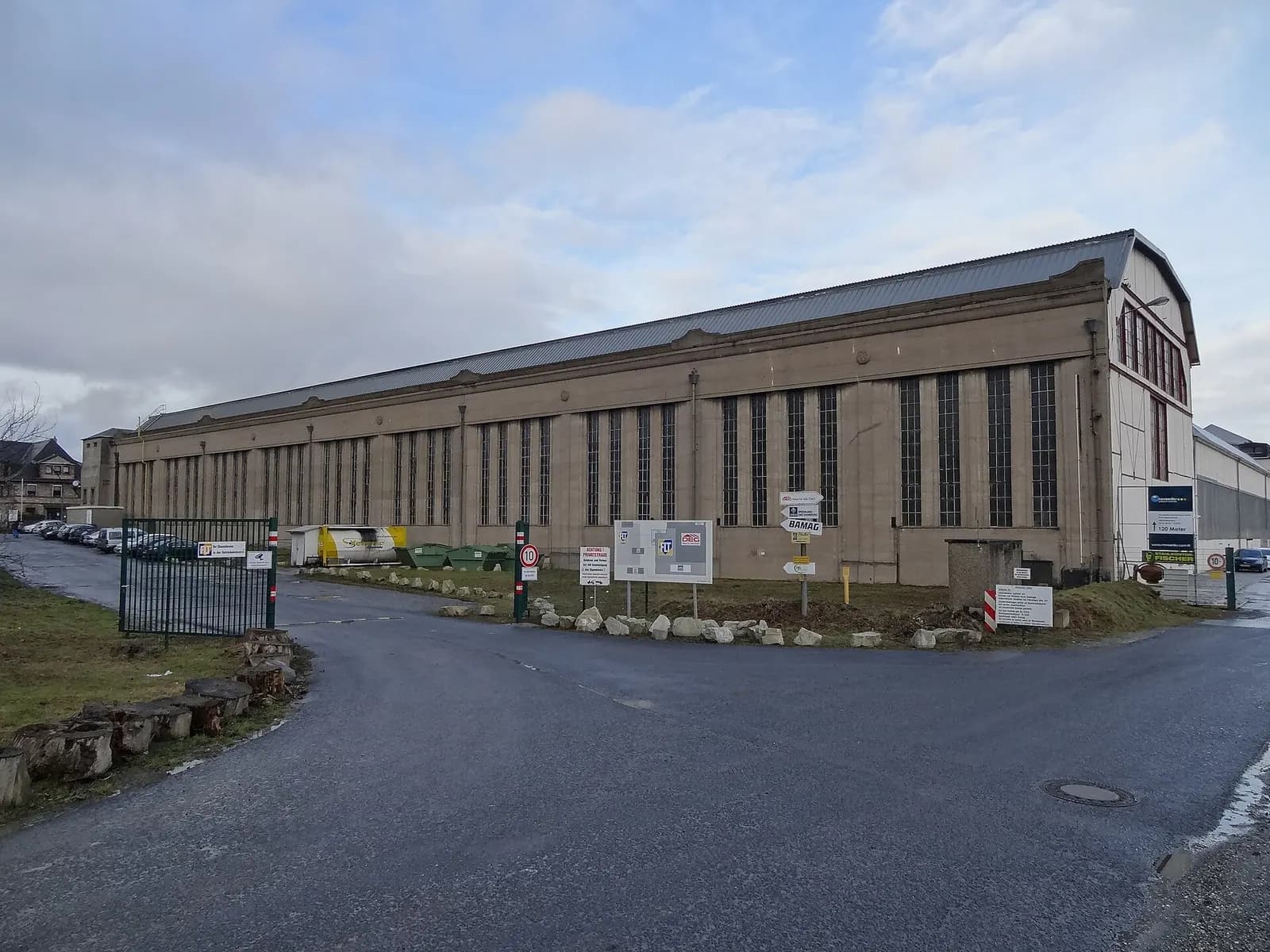 Long brick and glass machine-building workshop hall in Butzbach, Hesse, seen from the yard