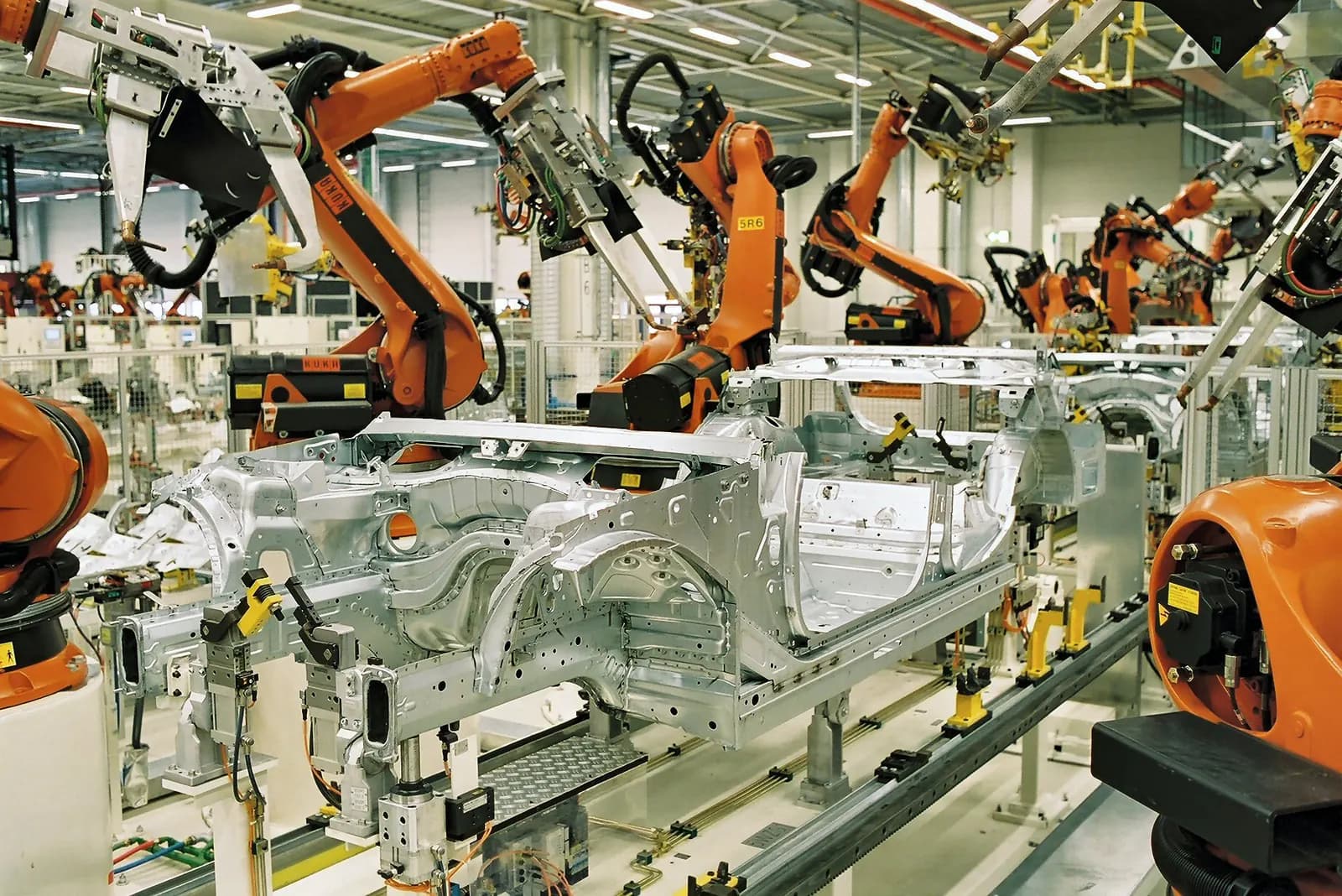 Orange industrial robots working on car bodies in the body shop of the BMW plant in Leipzig