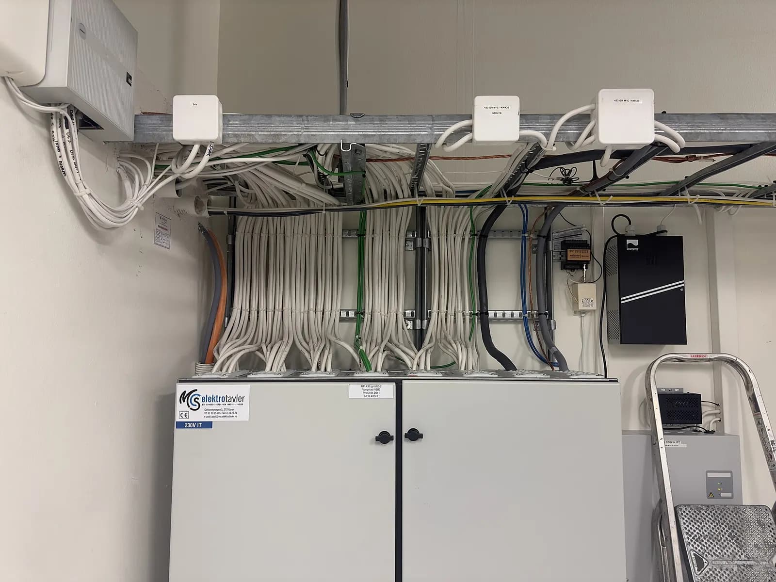 Plant room with closed electrical control cabinets and cable trays running along the ceiling
