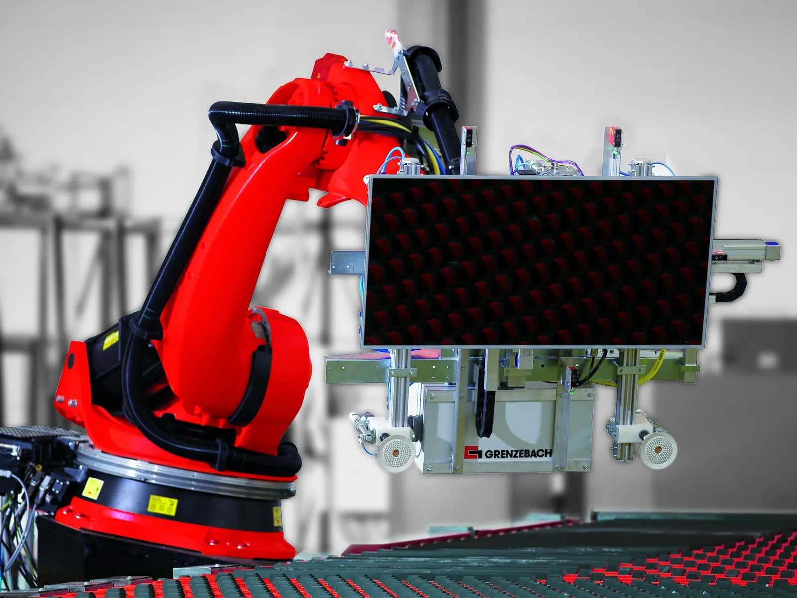 Red industrial robot handling a solar module on an automated production line