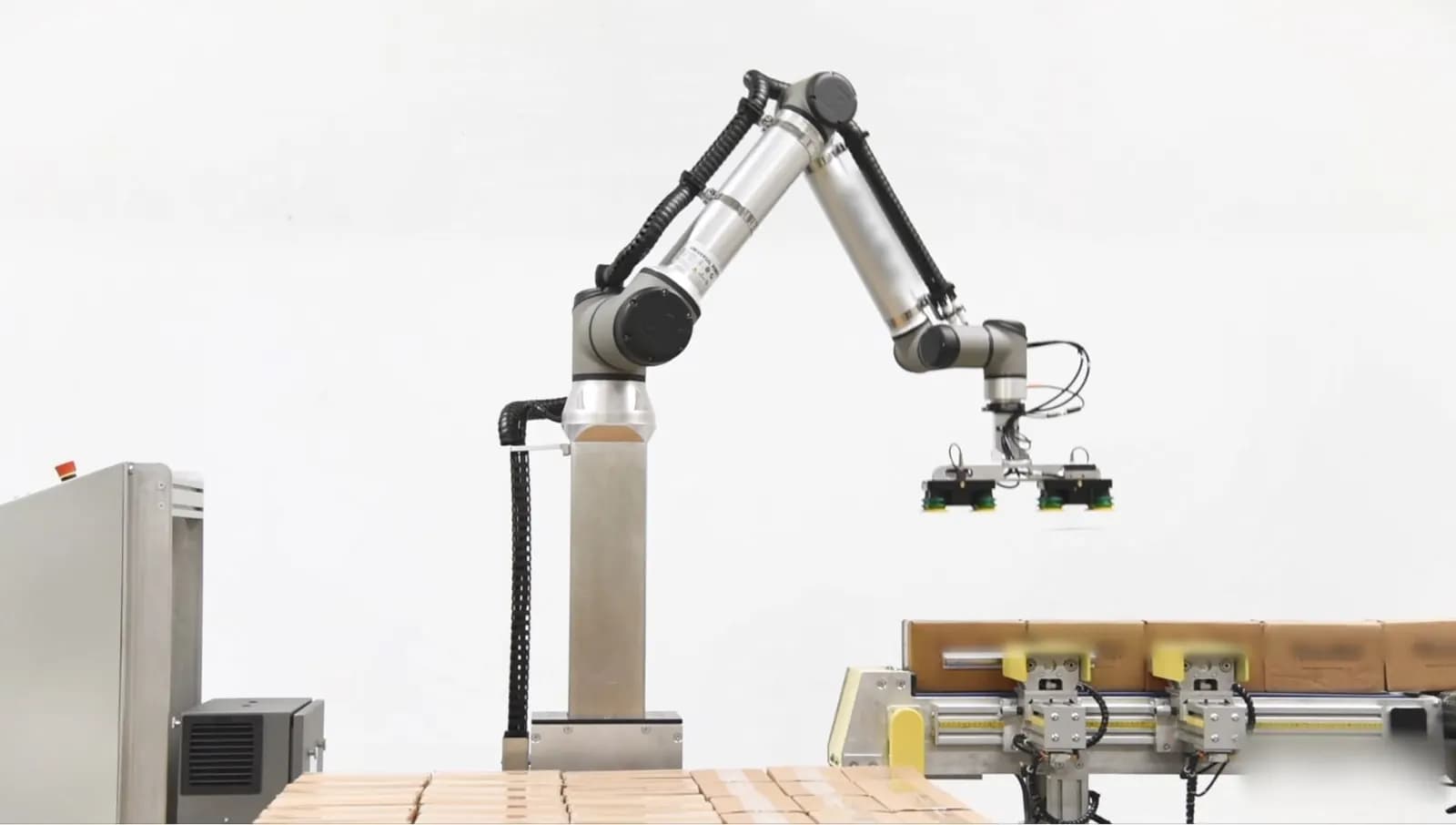 Collaborative robot arm on a lift column palletising cartons from a short conveyor