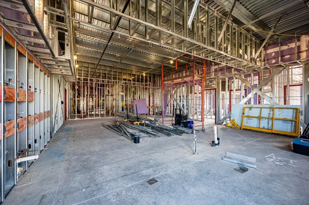 Empty new building interior under construction with exposed steel stud walls, a bare concrete floor and stacked metal framing