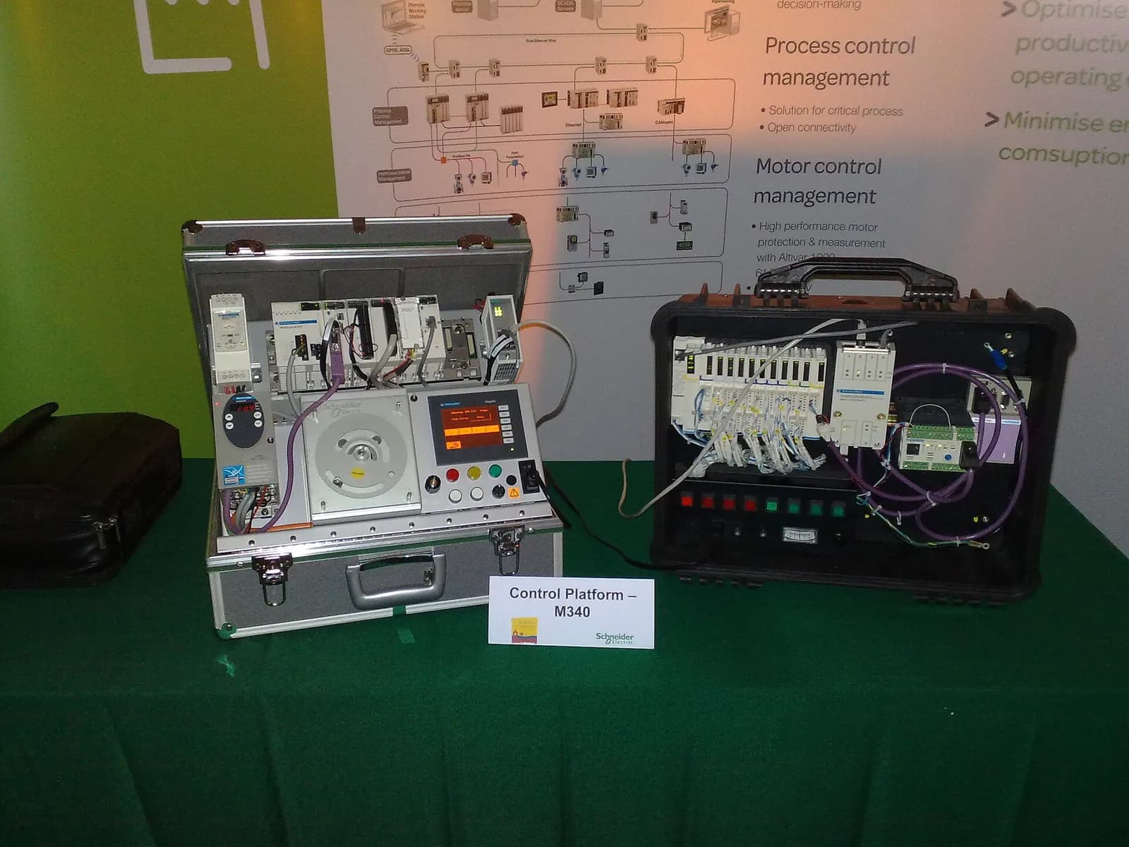 Two portable PLC training kits with I/O wiring and an HMI on display at an automation forum