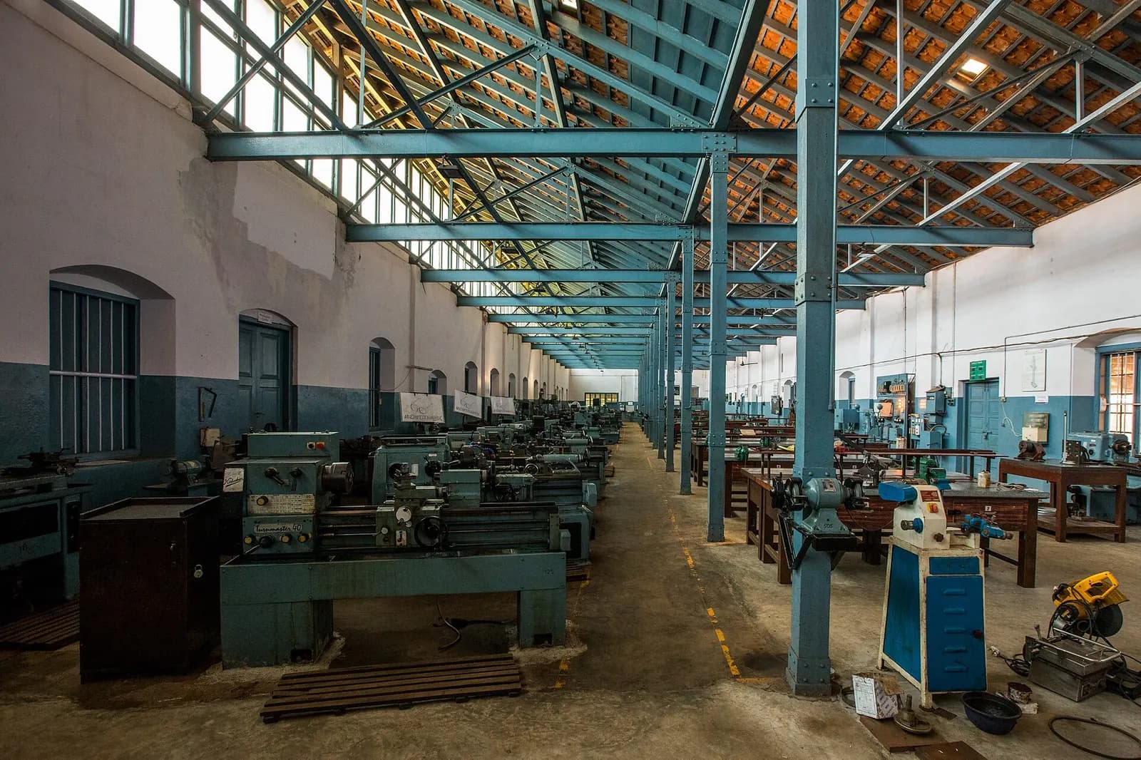 Long workshop hall of an industrial training institute in India with rows of lathes and machine tools under a steel roof