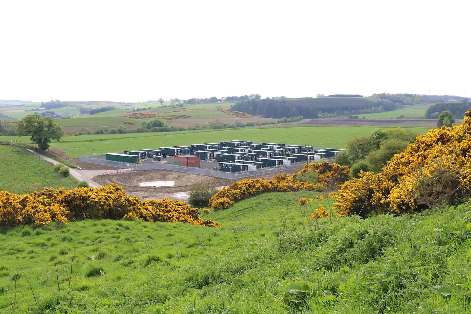 Rows of battery storage containers at the Camilla battery storage facility in Fife farmland