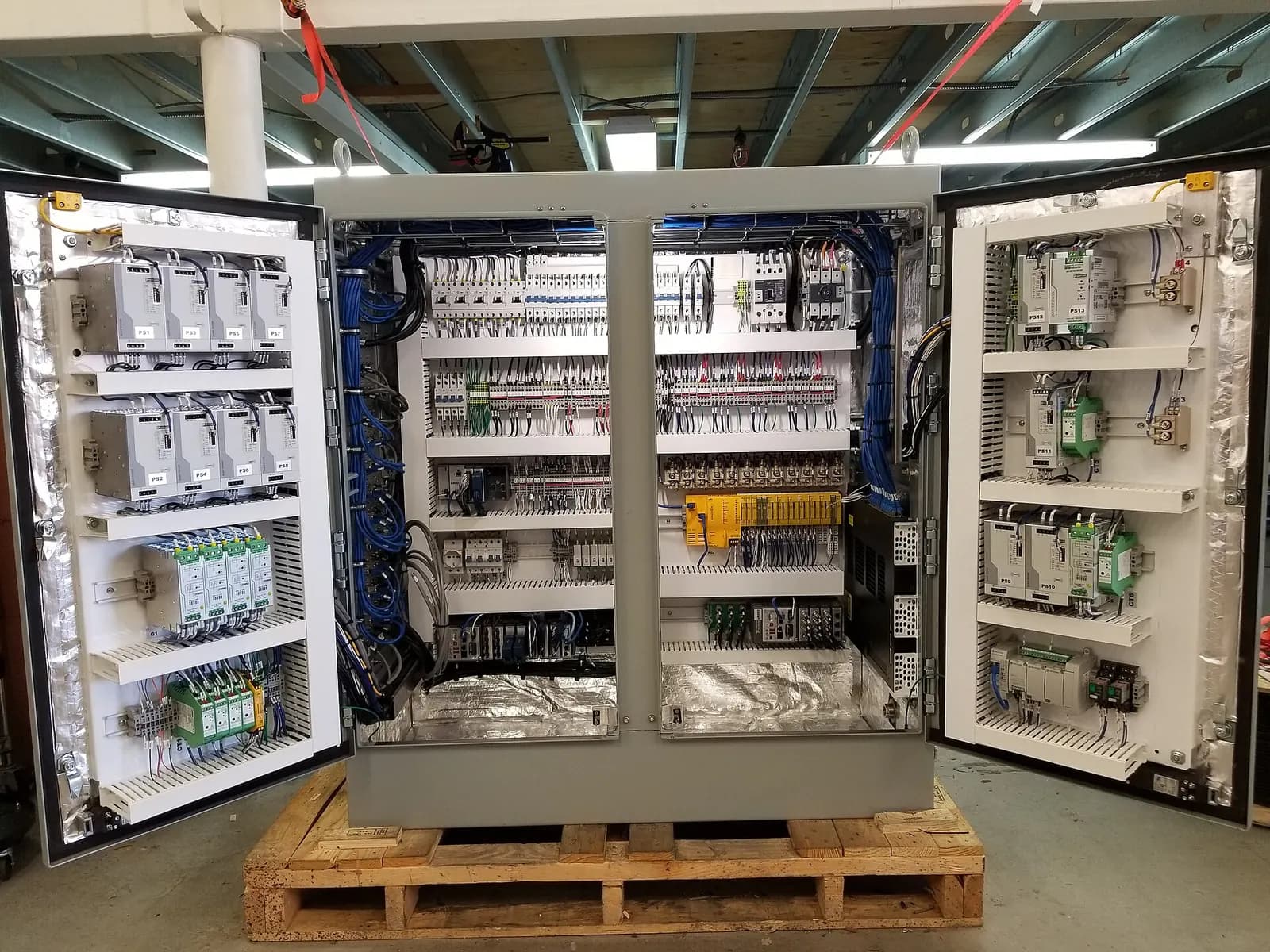 Open control cabinets on a pallet showing PLC modules, terminal rails and wiring ducts