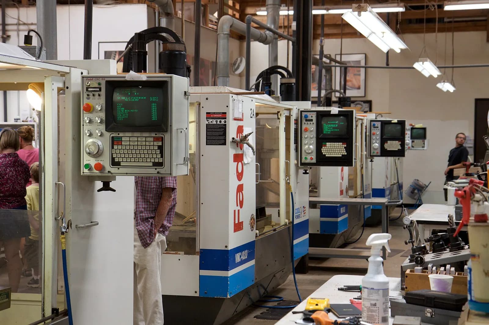 Row of CNC machining centres on a factory floor with an operator at the far end