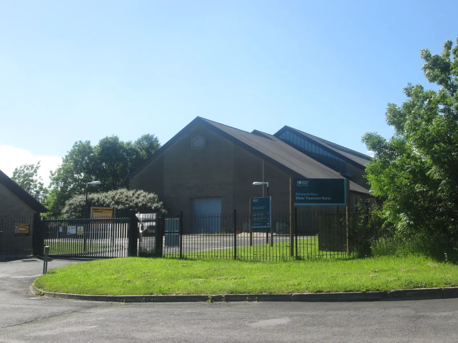 Entrance and low brick buildings of Ashworth Moor Water Treatment Works under a blue sky