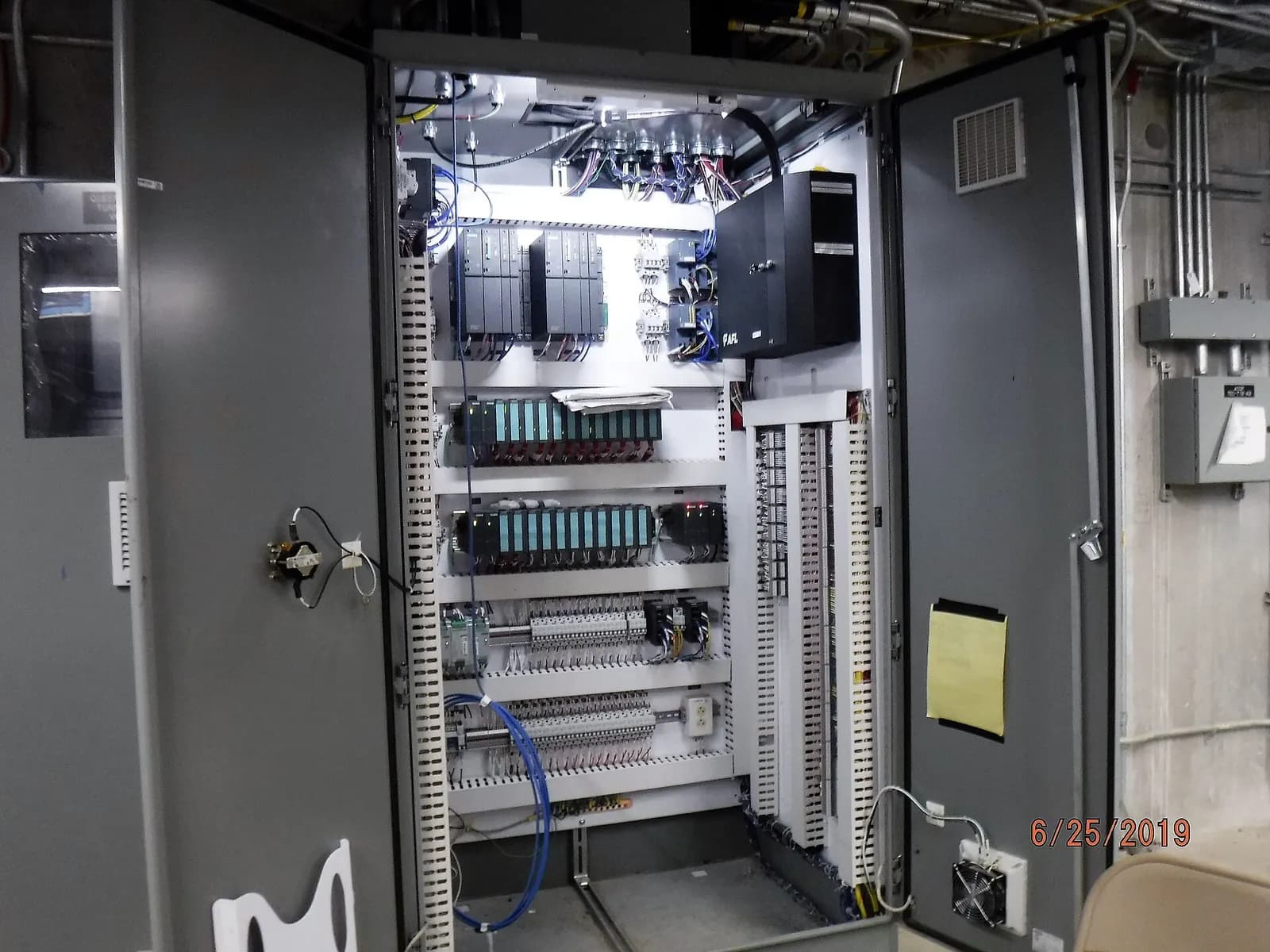 Open control cabinets with PLC racks and terminal wiring during a SCADA upgrade