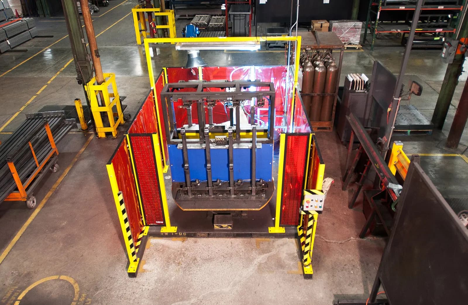 Robotic welding cell inside red and yellow safety guarding on a factory floor