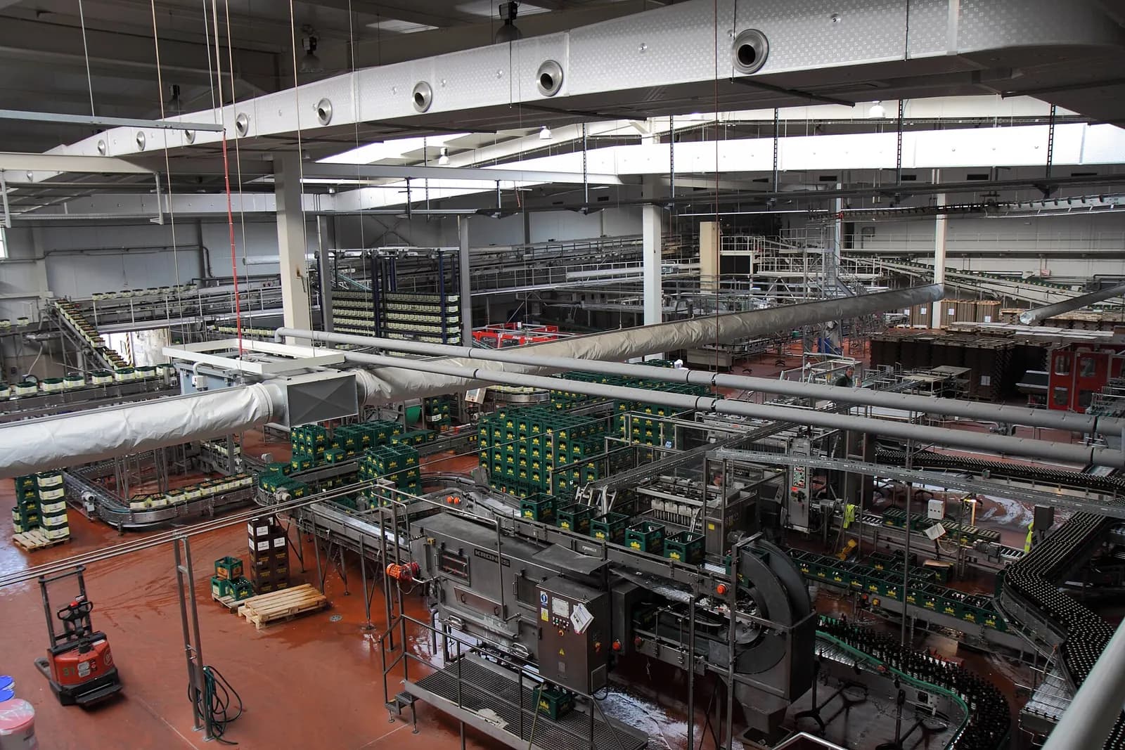 Bottles moving through a filling and conveying line in a large brewery hall