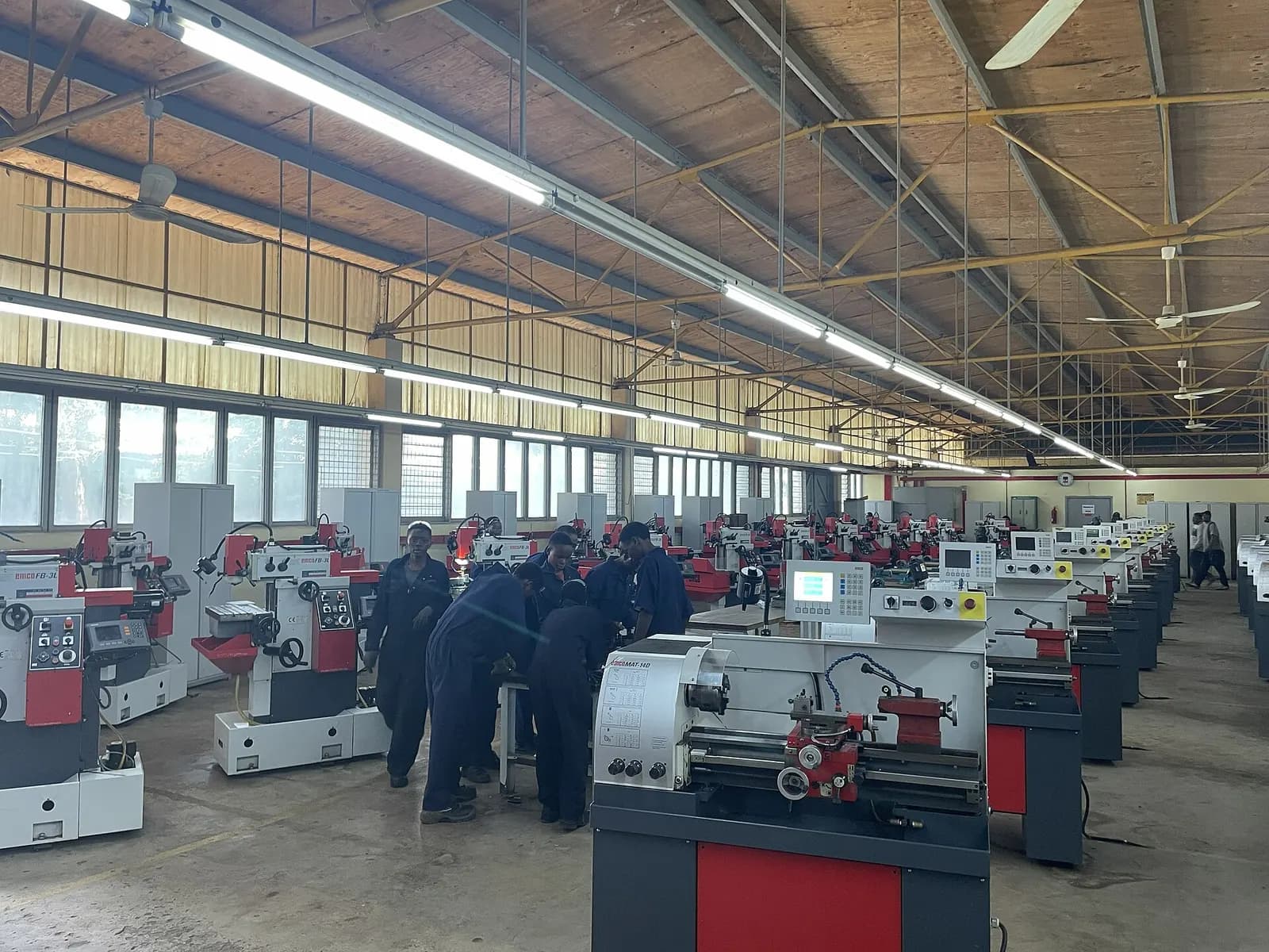 College mechanical engineering workshop with rows of lathes and students working at the machines