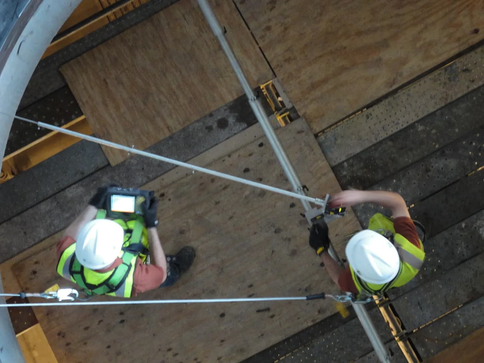 Overhead view of two technicians in hard hats using a laser alignment instrument on a pump at a pumping station.