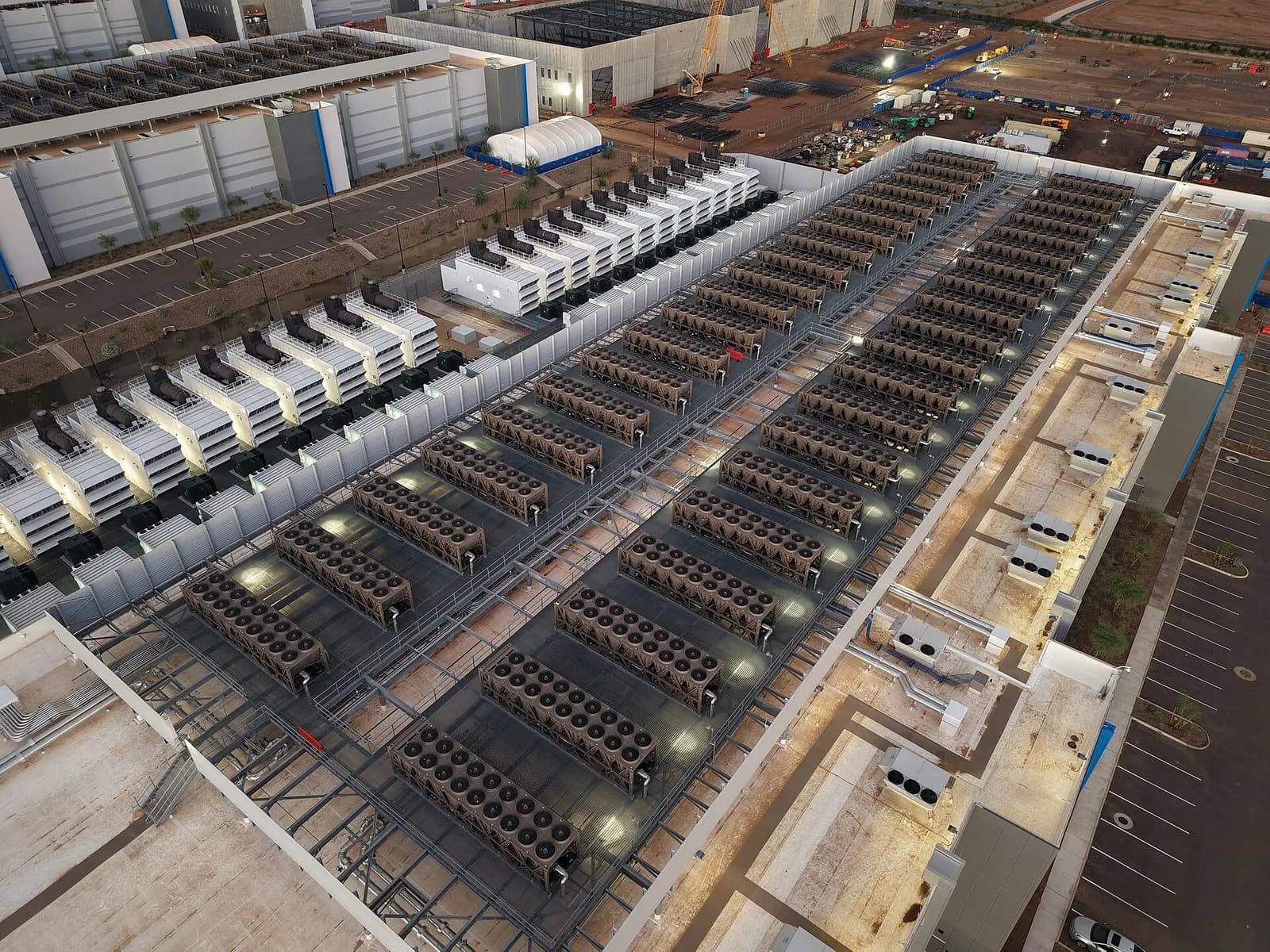 Rooftop of a data centre with rows of cooling units and backup generators seen from above.